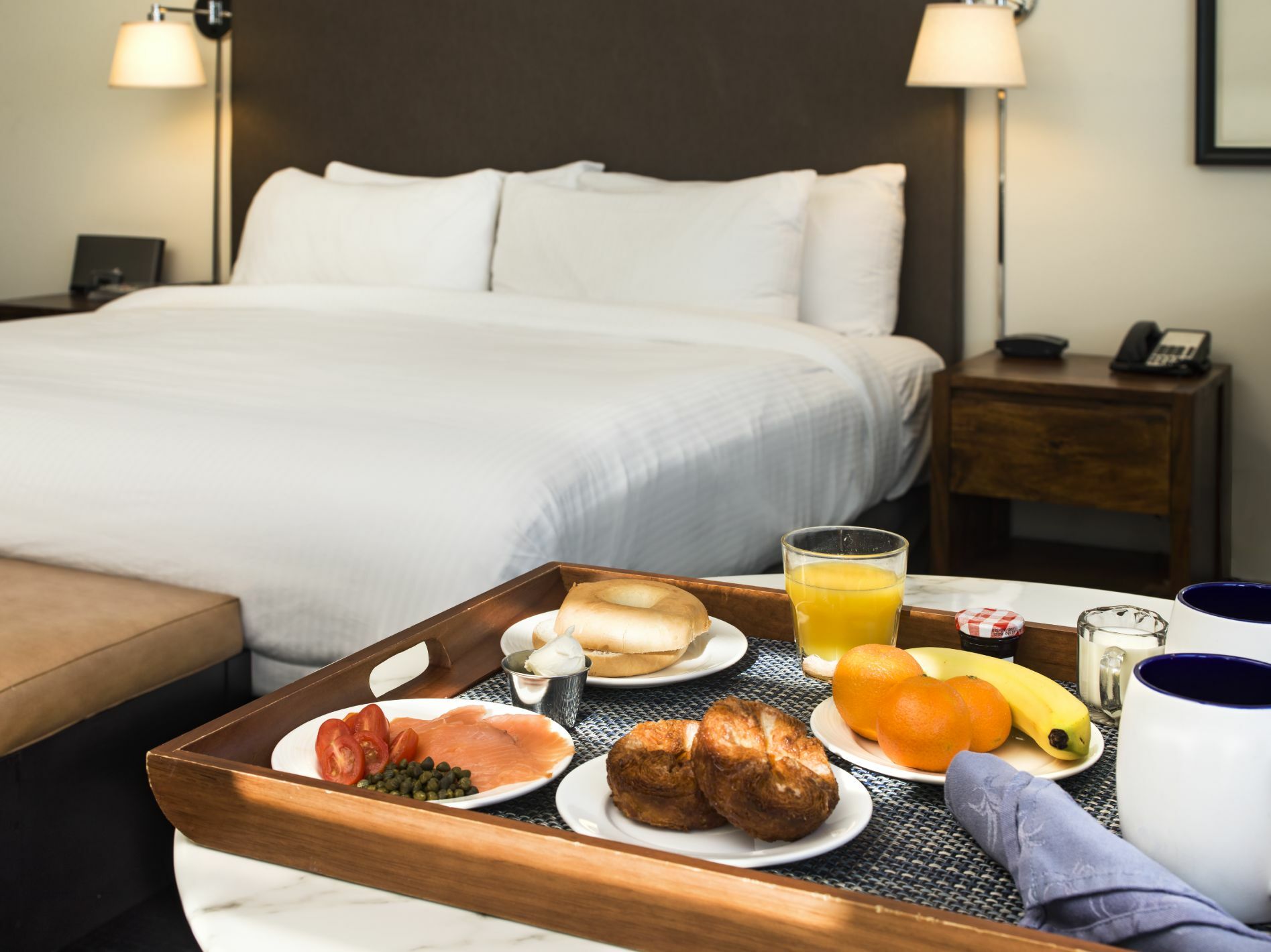 Continental breakfast tray next to the bed with bagel, cream cheese, lox, capers, tomatoes, muffins, fresh fruit, coffee and juice.15-1464.jpg