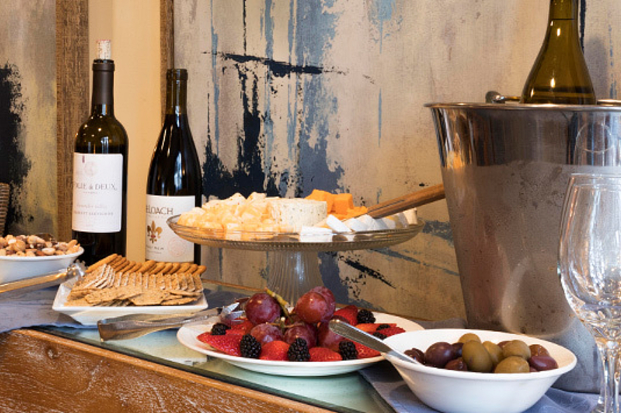 Cheese, crackers, olives, nuts, and fruit spread on a hutch with three bottles of winewine-4-3.jpg