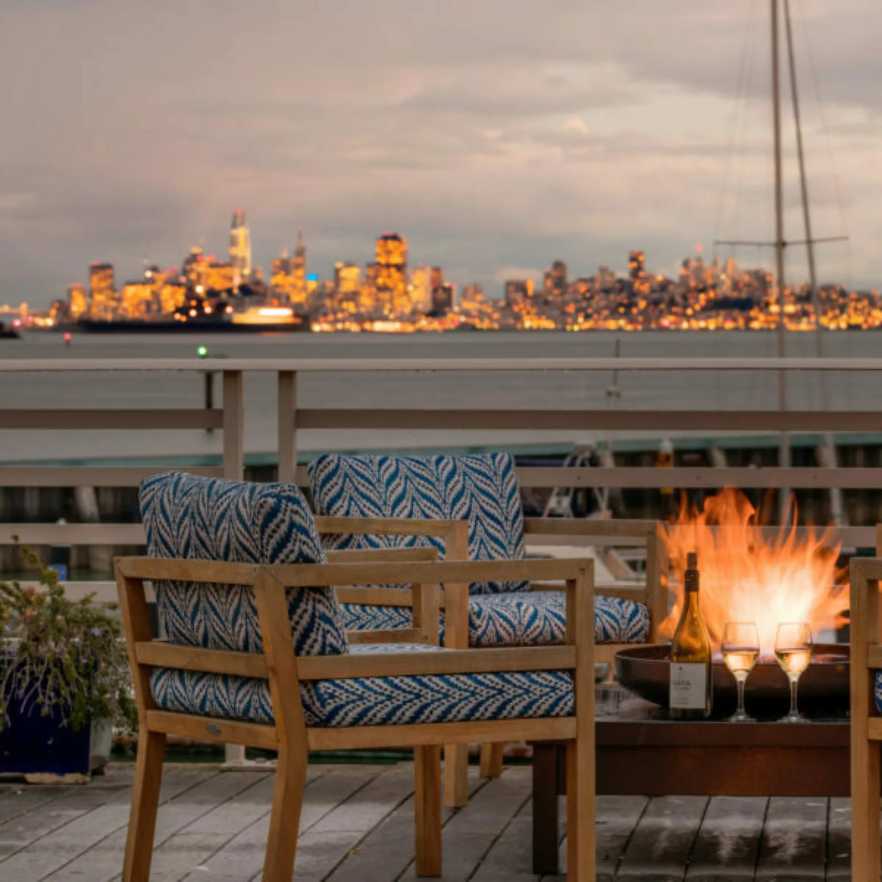View of the San Francisco skyline with buildings aglow at sunset from the Grand Deck with fire roaring in the fire pit