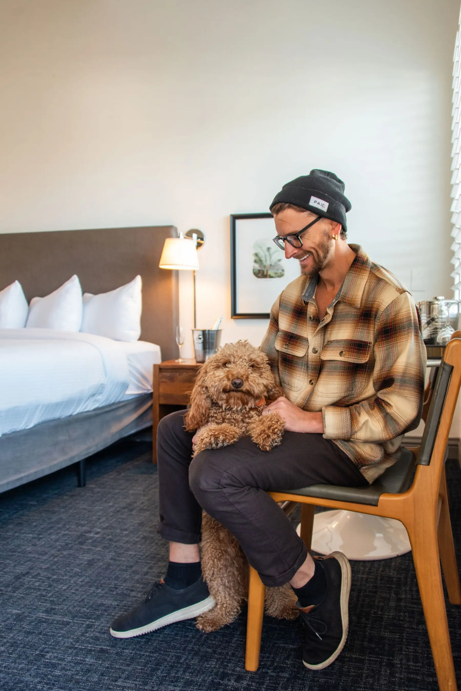 man sitting on chair in hotel room with his fluffy cinnamon colored dog who is look directly at the camera and smilingWEH-man-and-dog.jpg
